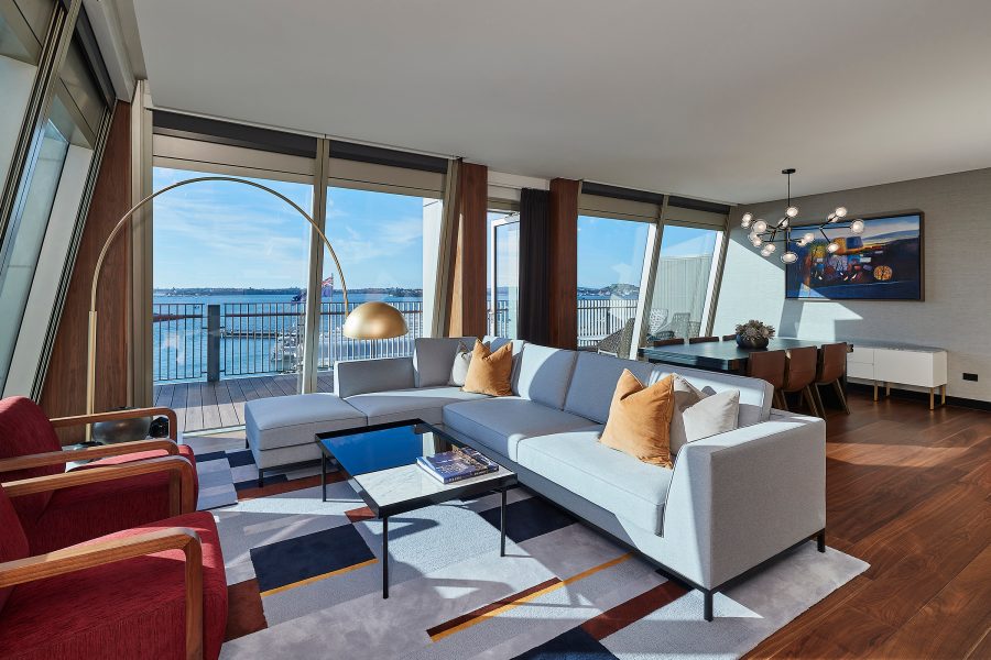 An Executive Rooftop Suite in Park Hyatt Auckland with spacious living and dining areas and a wrap-around balcony with Harbour Bridge and city views. 